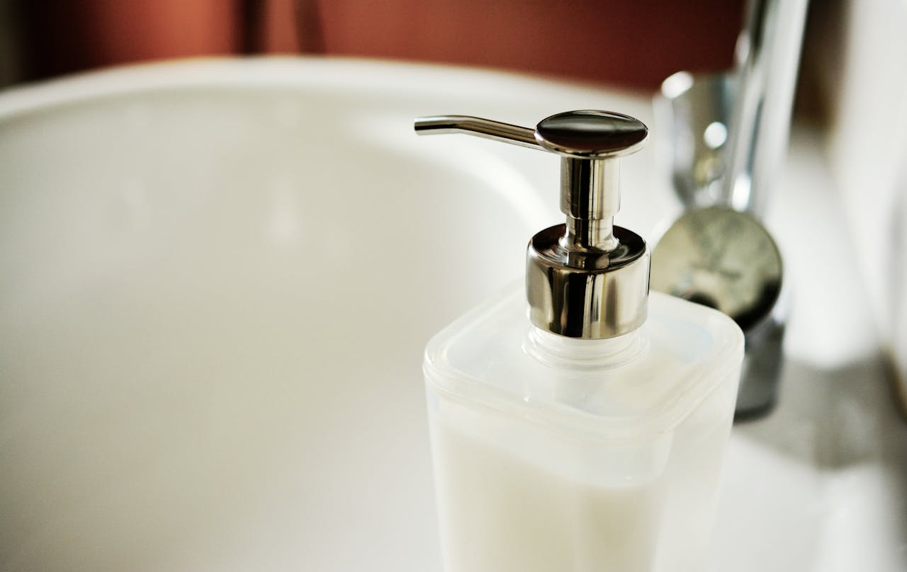 Close-up of a modern soap dispenser beside a sink in a clean bathroom.