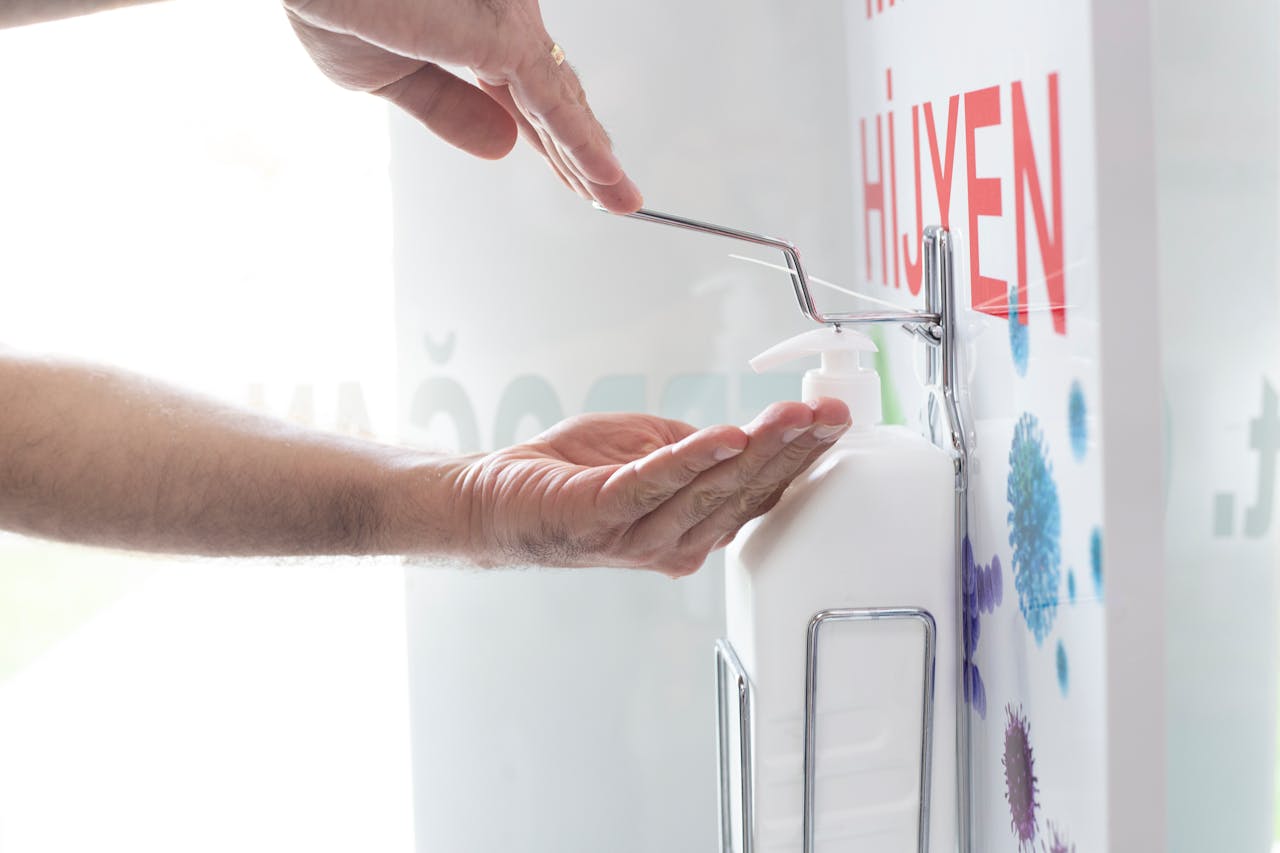 Close-up of hands using a liquid disinfectant dispenser in a clean environment emphasizing hygiene.